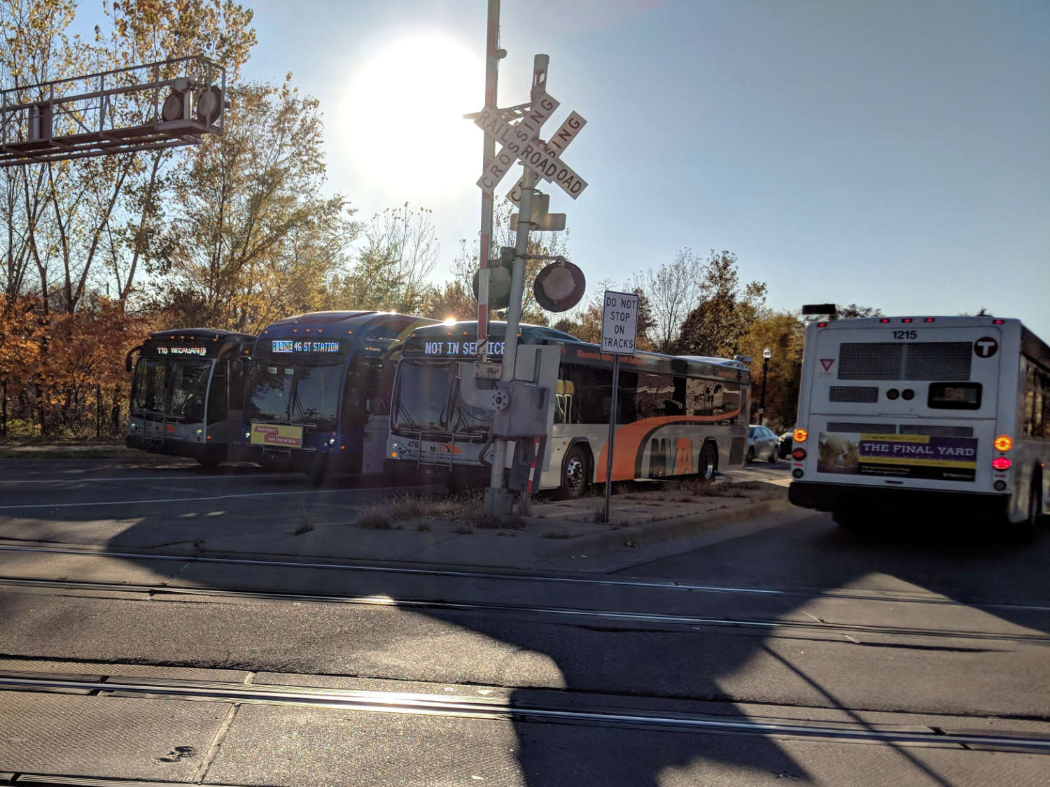 buses sitting next to light rail crossing