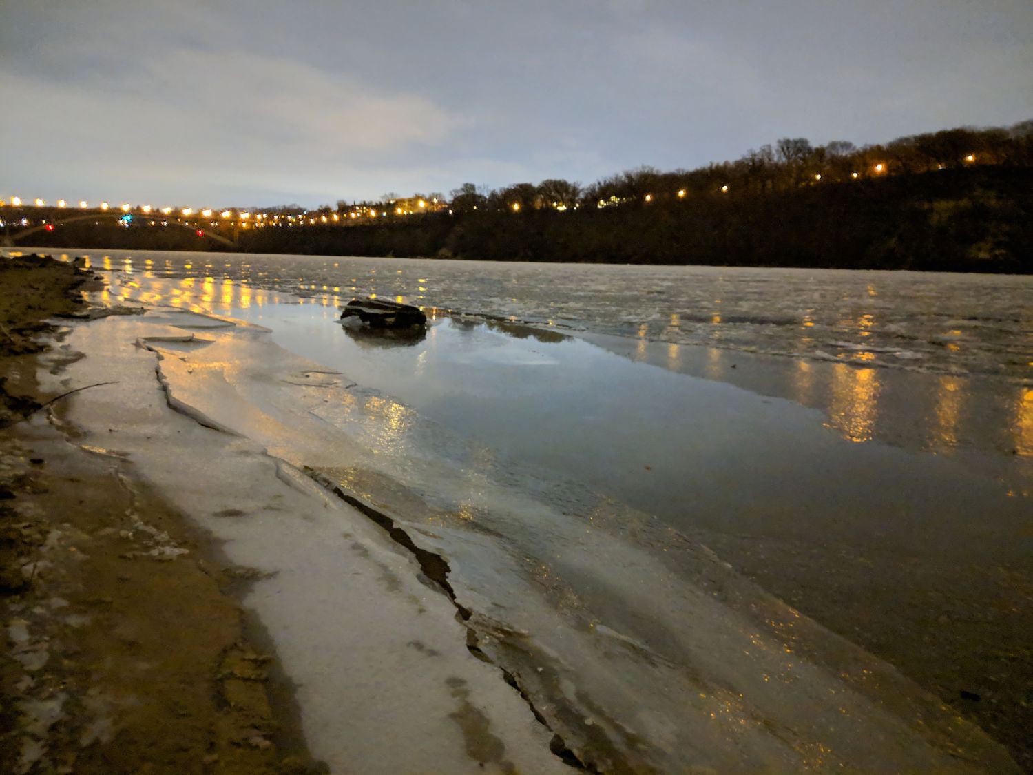 River with ice along shore and reflections of street lightrs