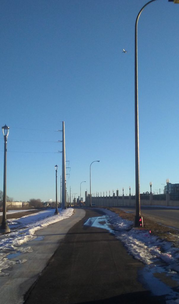 bicycle path framed by light and power poles with blue sky