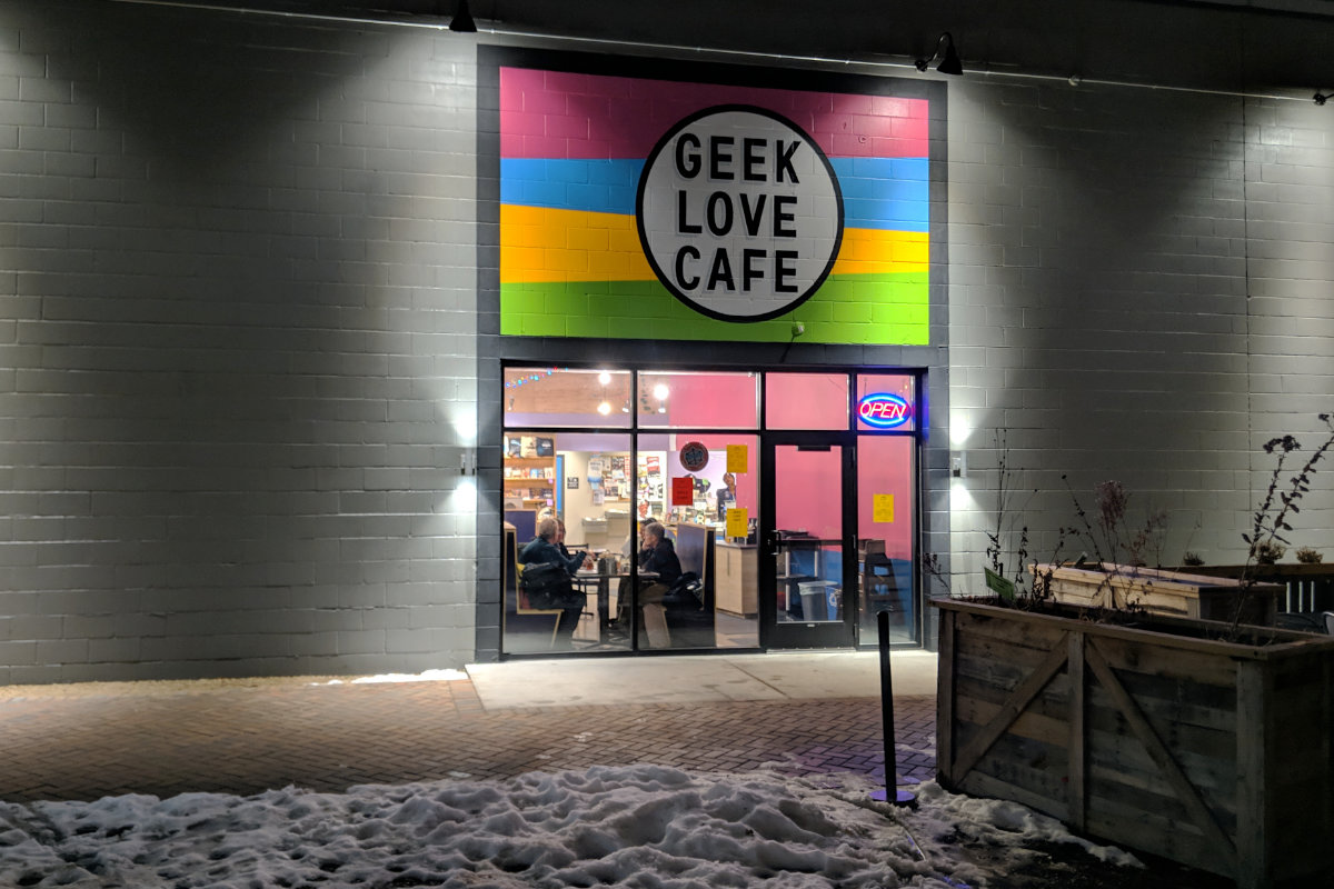 Outside view at night of Geek Love Cafe building entrance and window with diners