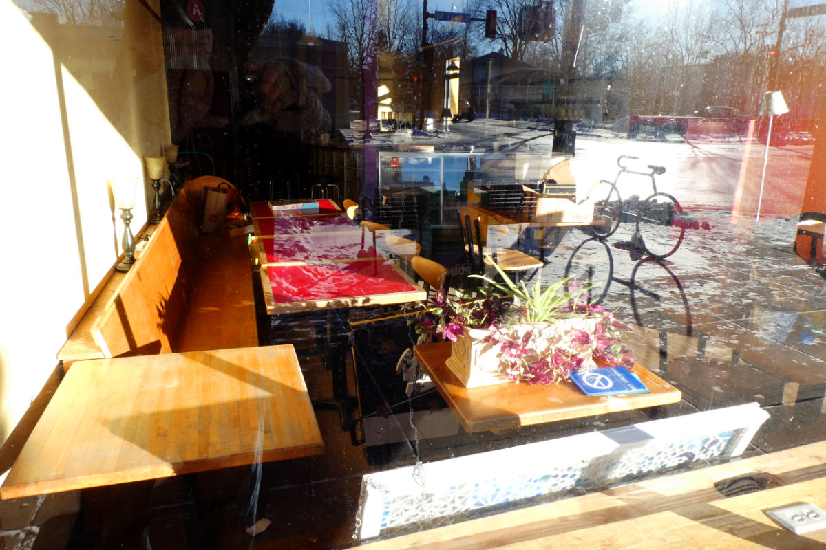 storefront window into empty bench and tables with street reflections