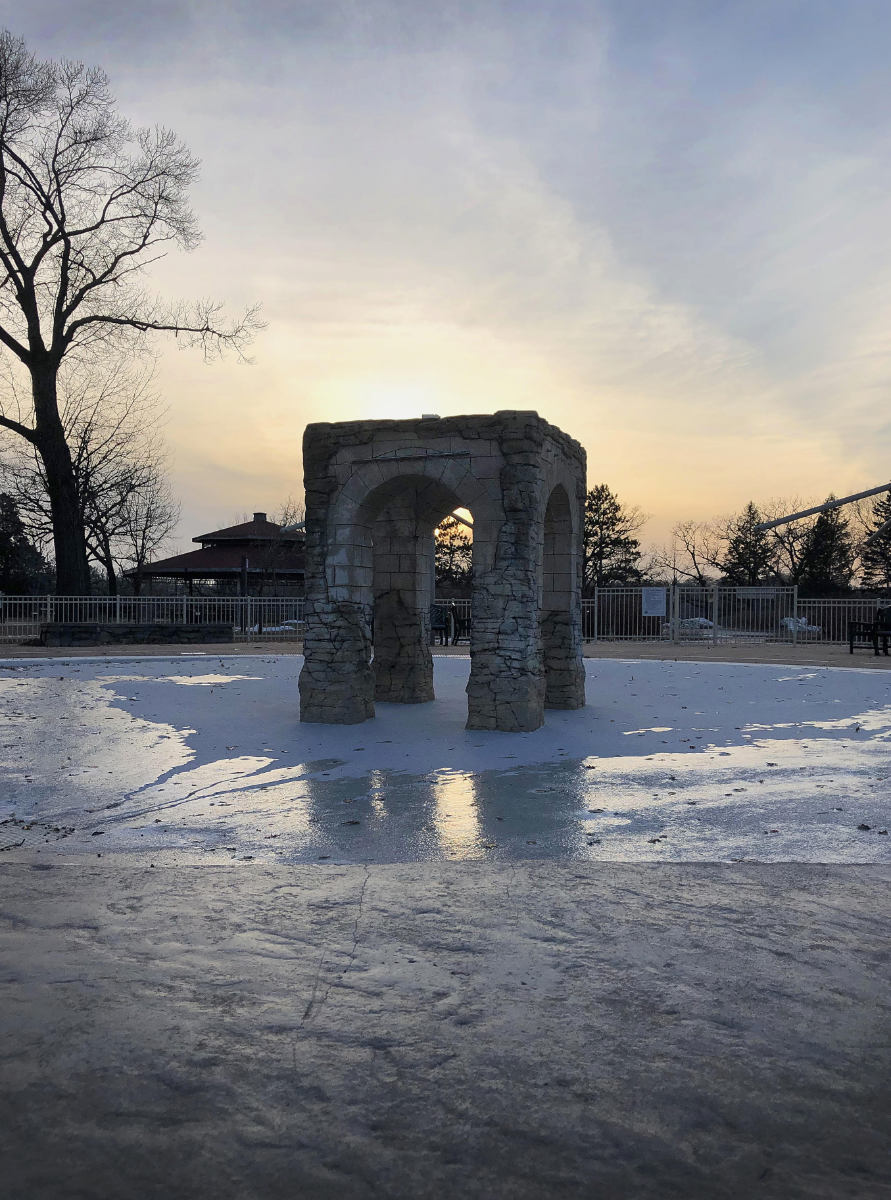 Four-pillared square stone structure in circular iced pond with sunset background