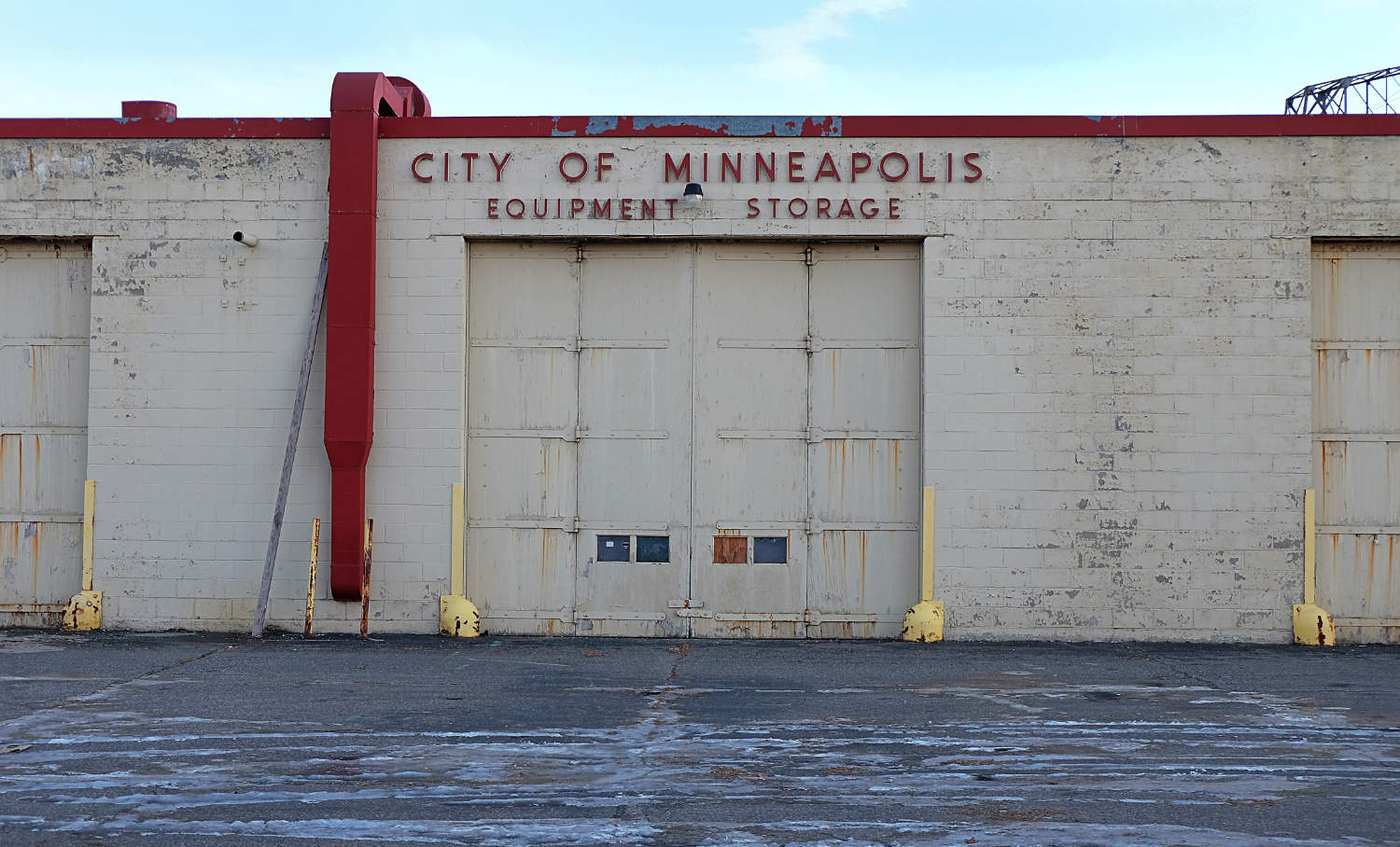 Cinder block building with City of Minneapolis Equipment Storage sign over industrial overhead door