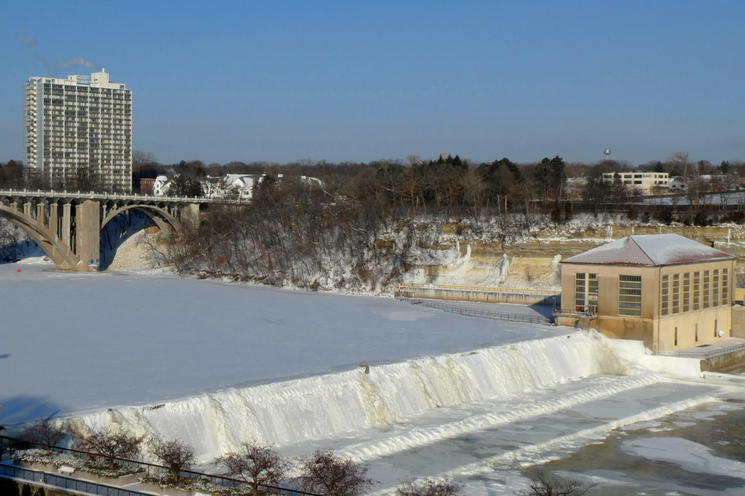 icy cascade over a dam on frozen mississippi river with old Ford power plant