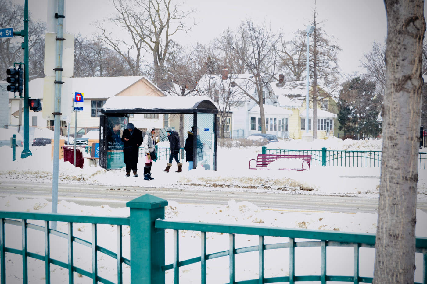 four people waiting at a bus stop with snow cover
