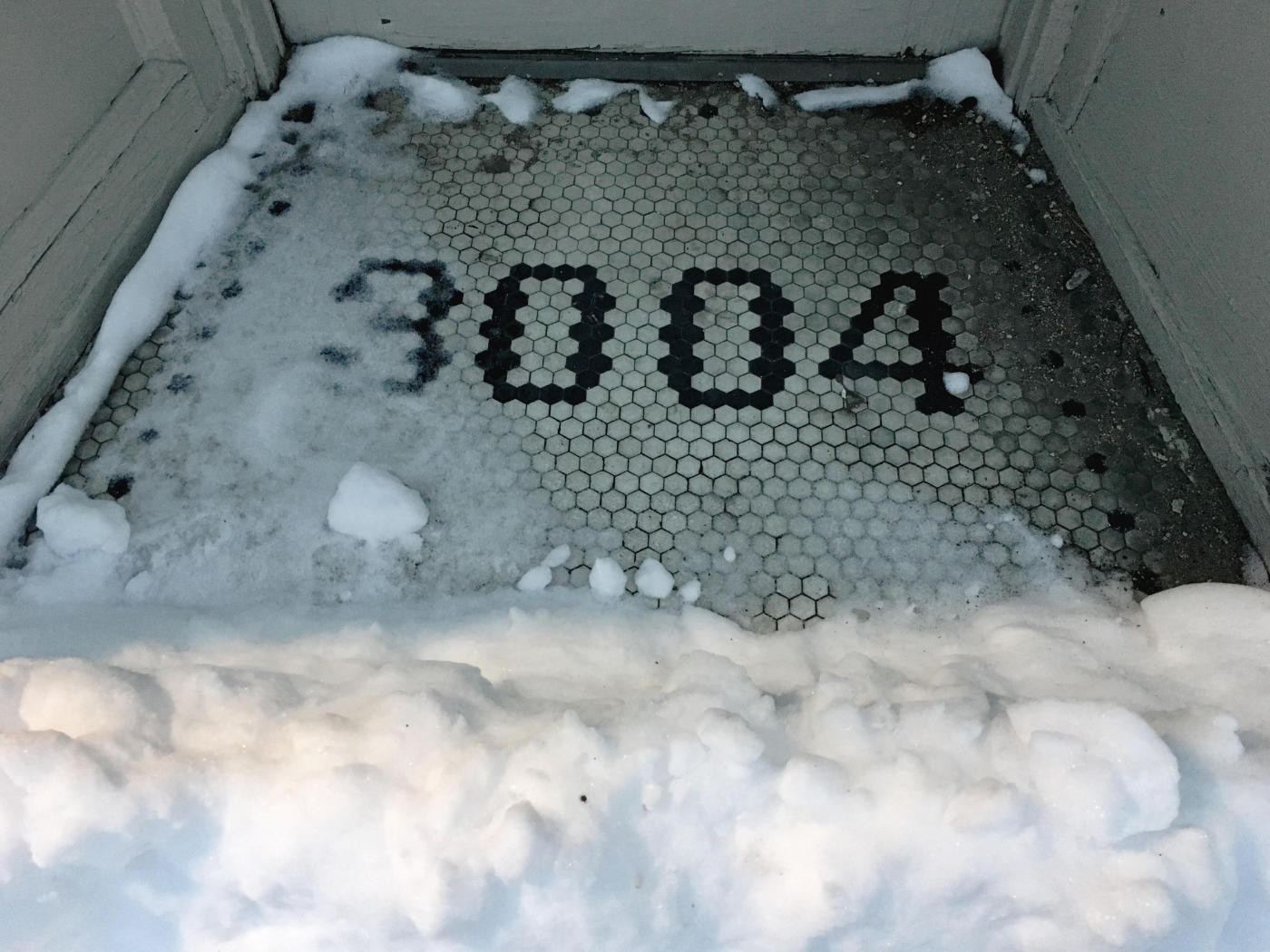 Tiled entryway floor with number 3004 in it, plus snow in the foreground