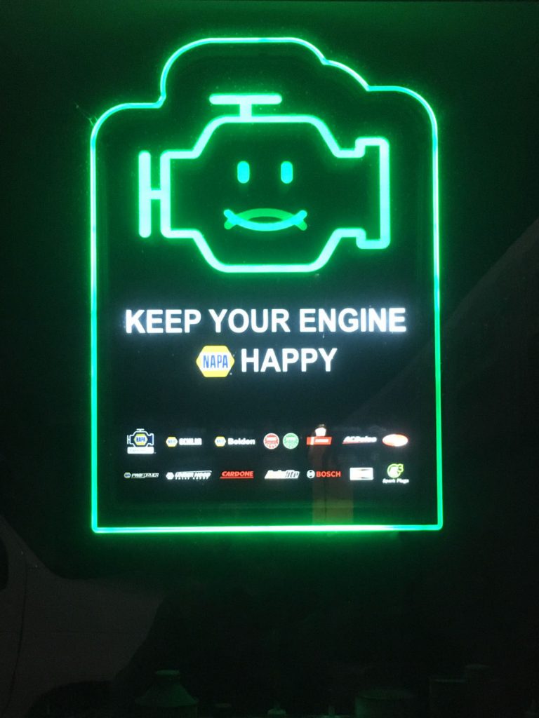 Green neon sign with engine-shaped smiley and words KEEP YOUR ENGINE HAPPY