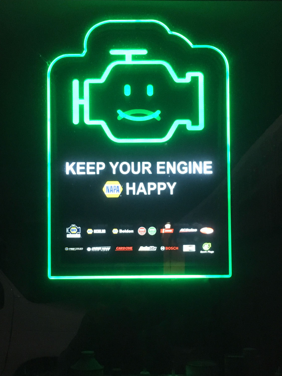 Green neon sign with engine-shaped smiley and words KEEP YOUR ENGINE HAPPY