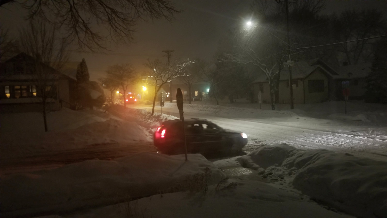 car stopped at snowy intersection at night