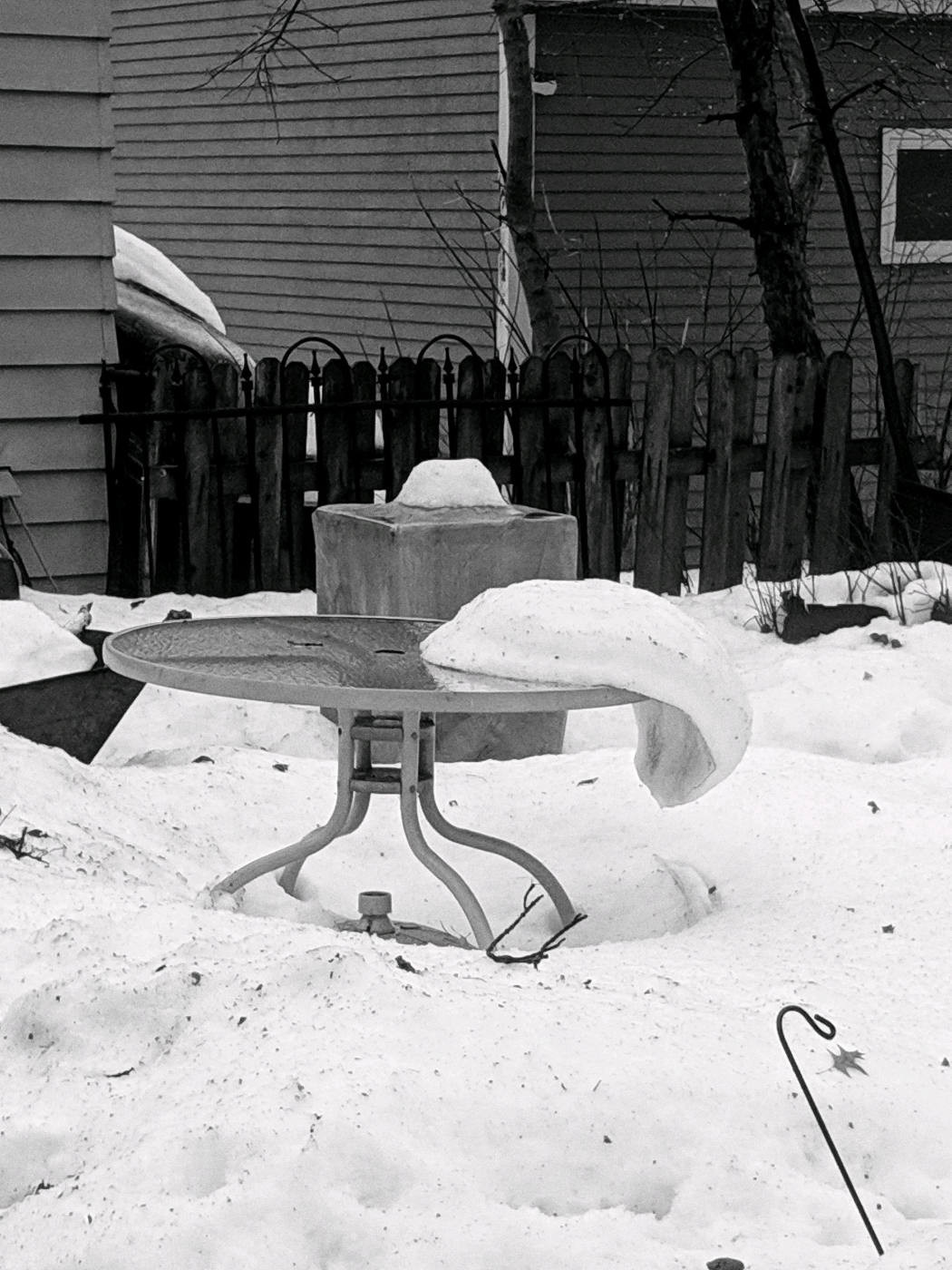 Snow slab sliding off a table in a backyard of snow