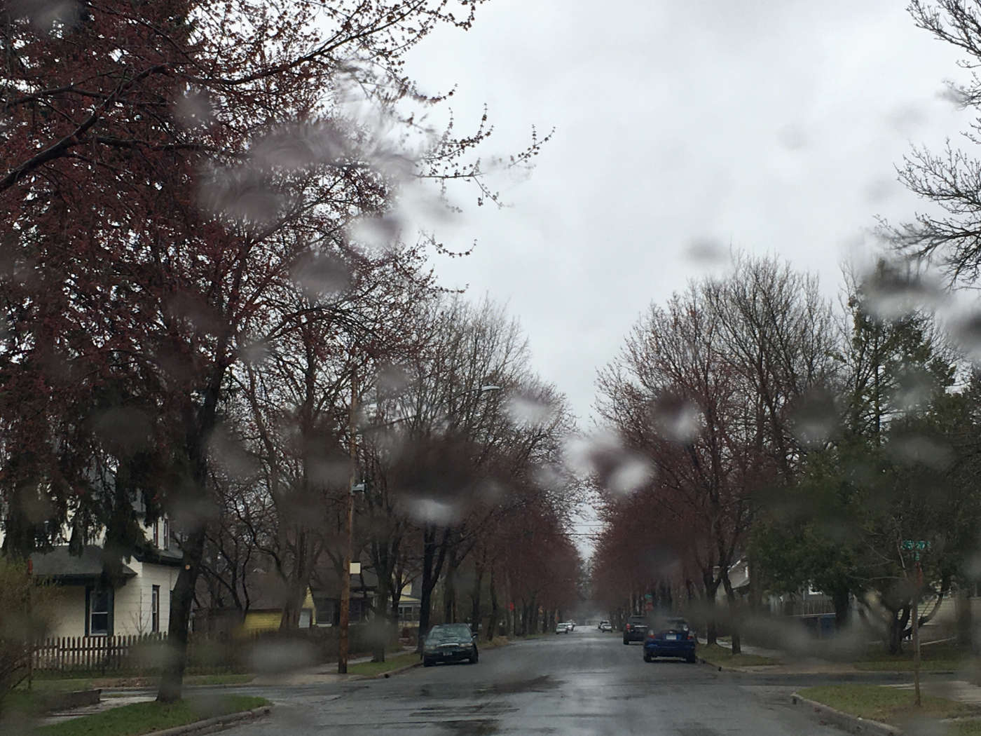 Rainy residential street with blurry drops on camera lens