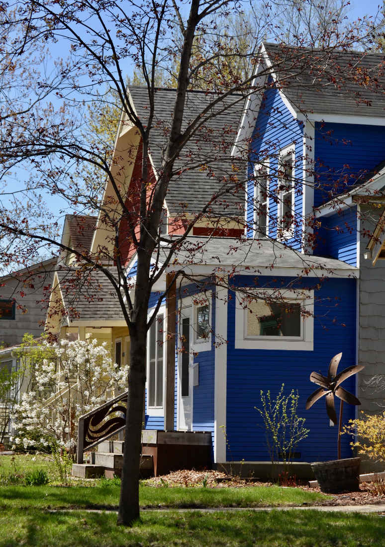roval blue two-story house from side with blossoming trees in yard