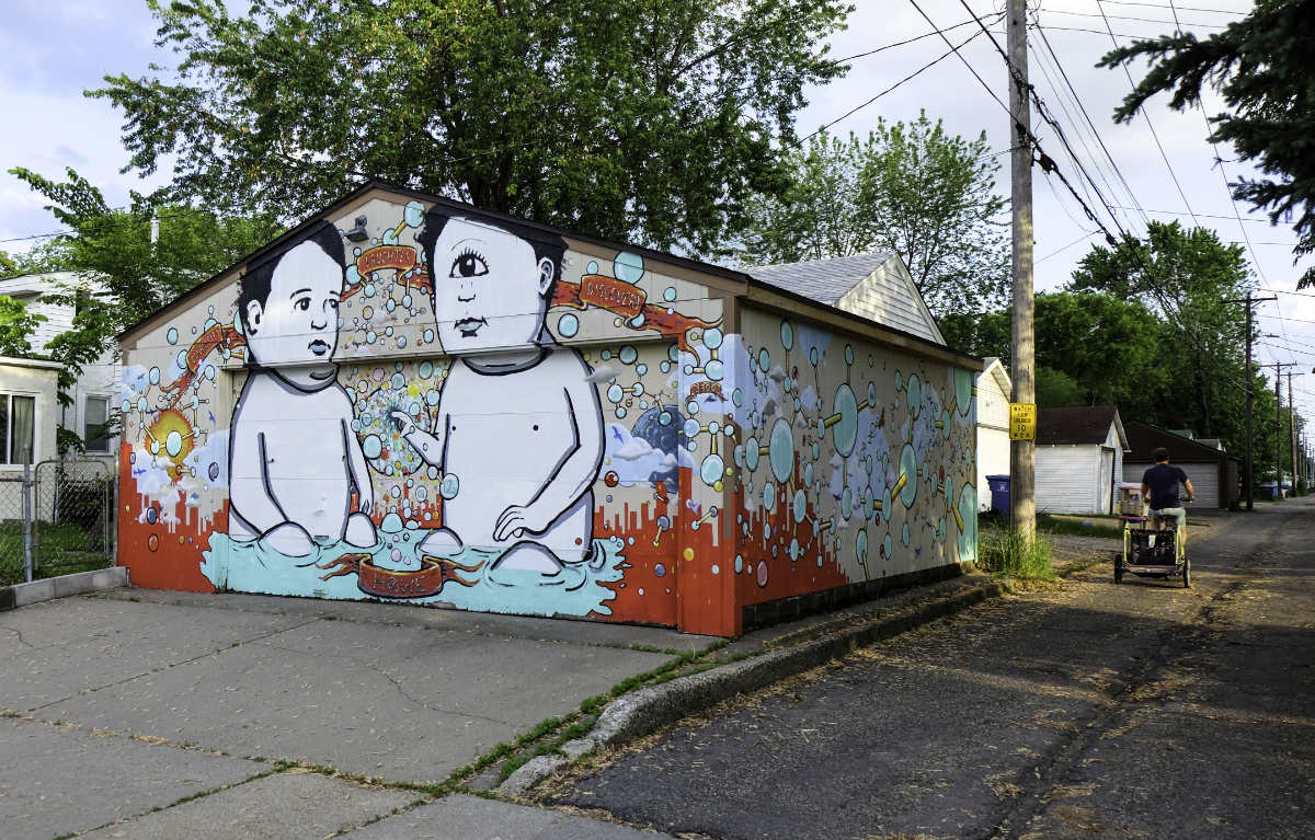 Garage wrapped with colorful mural with two giant babies, one is one-eyed.