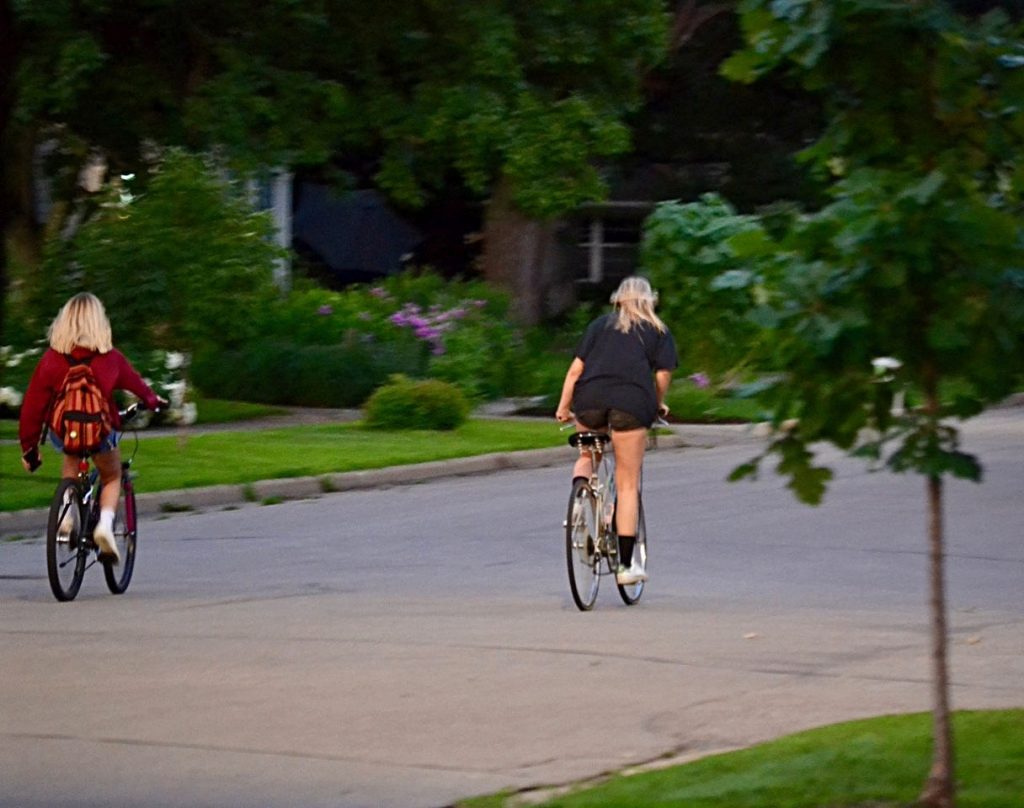 two people riding bicycles on the street scene from behind some distance away