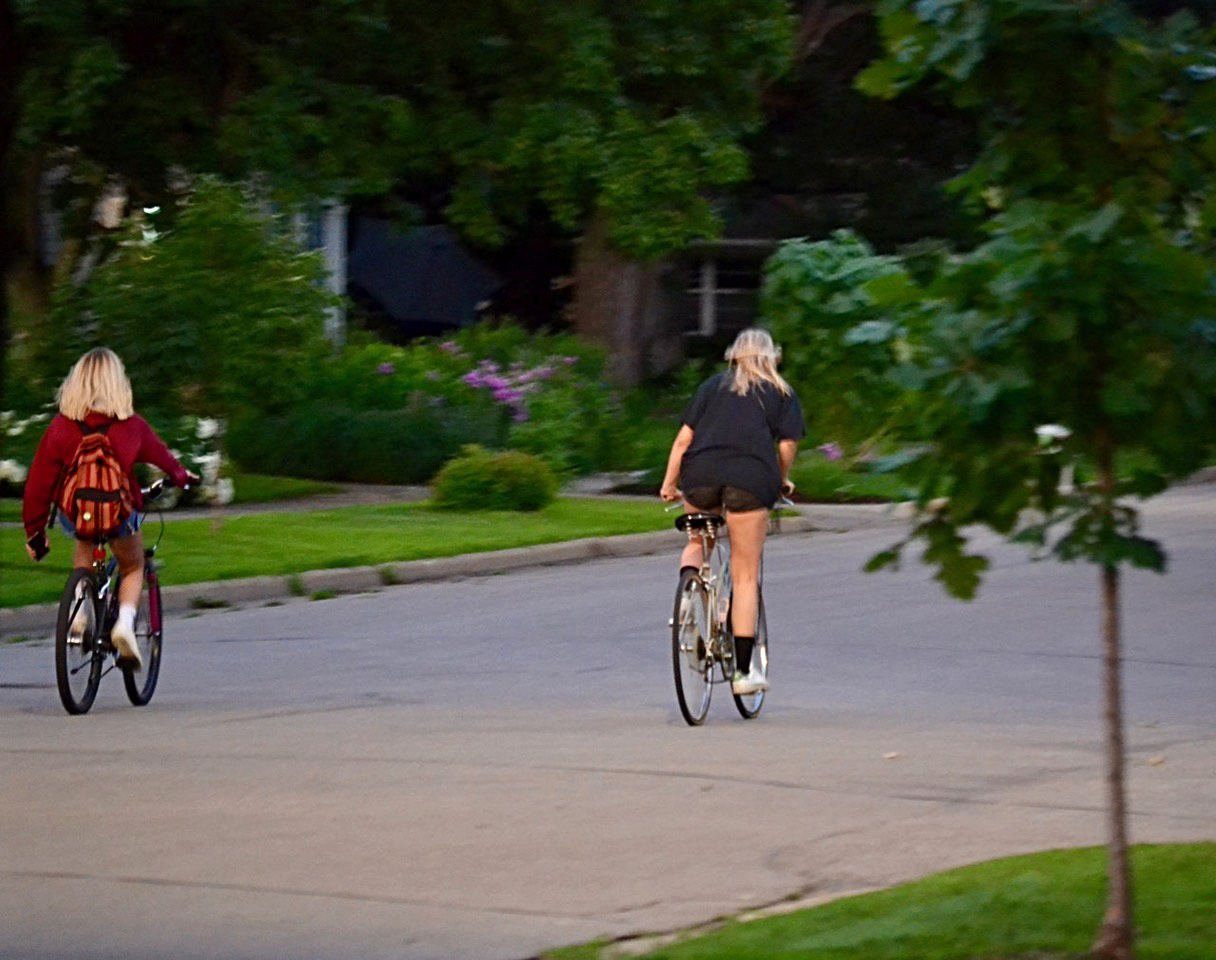 two people riding bicycles on the street scene from behind some distance away