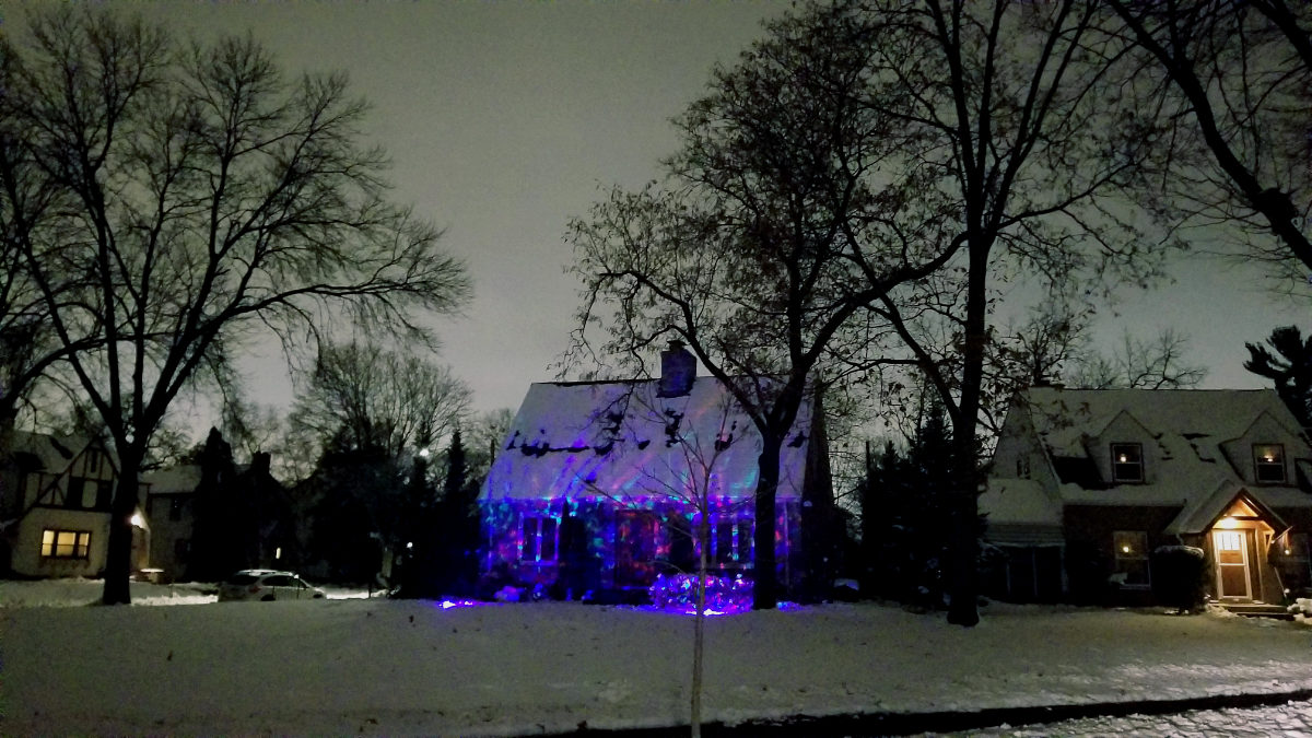 Nightscape with house in distance decorated with purplish holiday lights