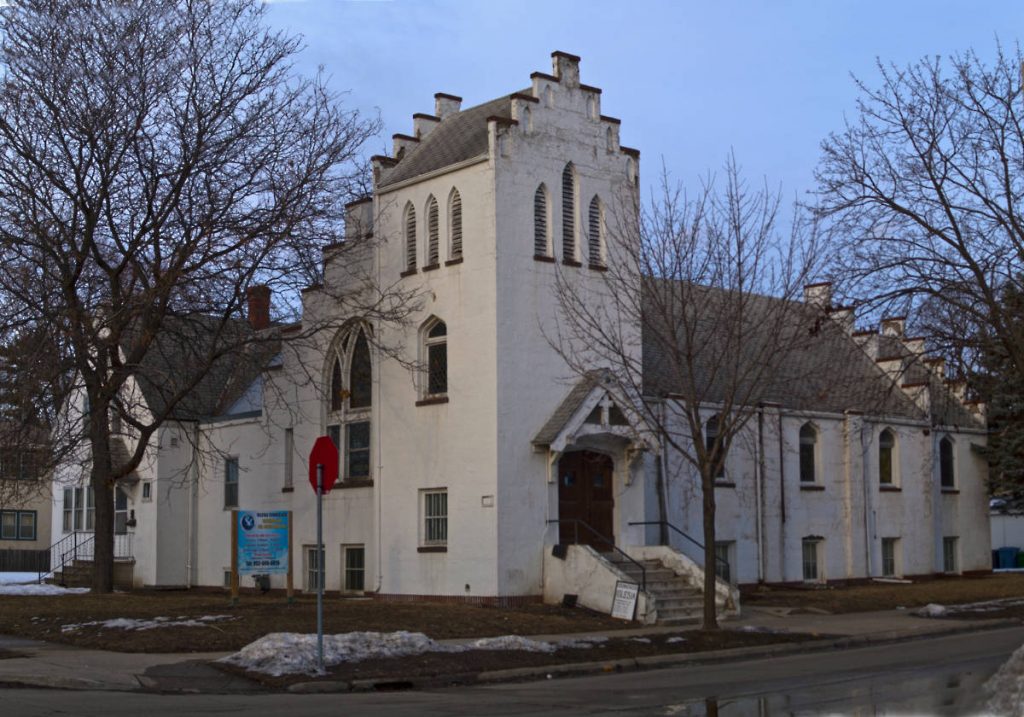 White corner church building with three-story tower, but no steeple