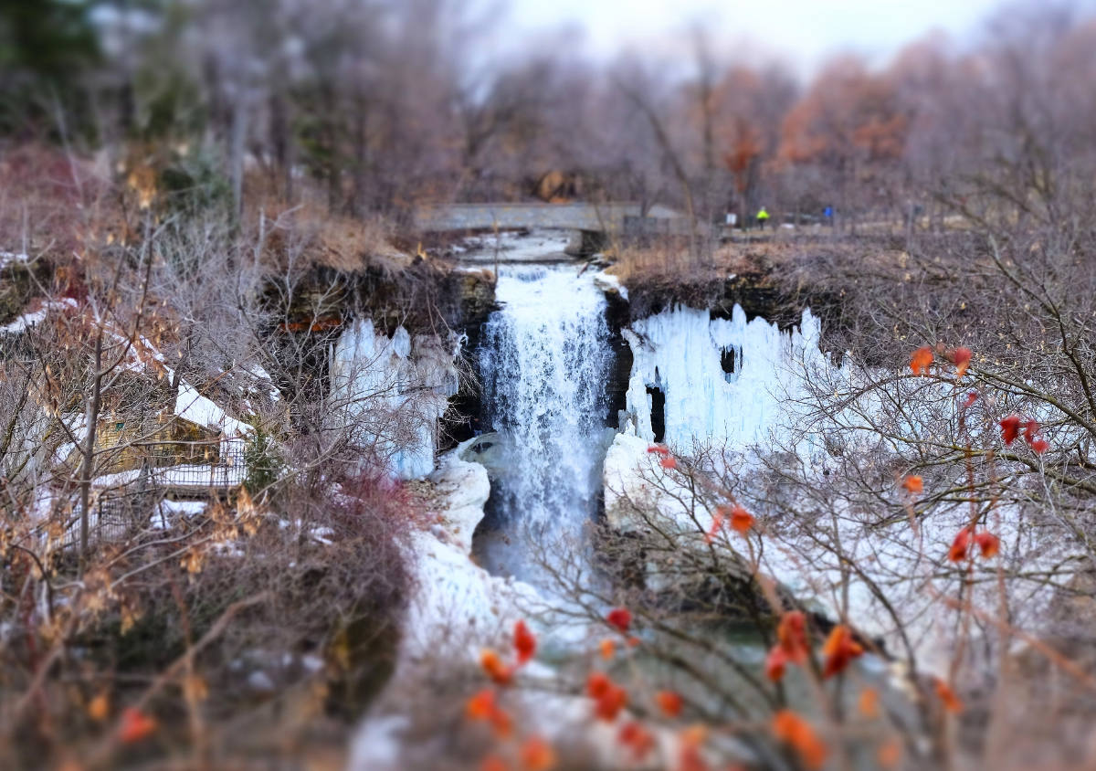 waterfall framed with icy cliffs on a gray day with brown trees and branches
