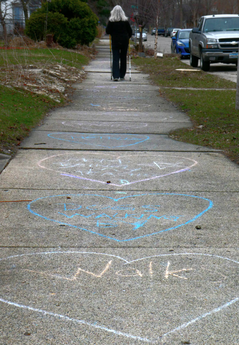 Sidewalk with chalk hearts with words in them.