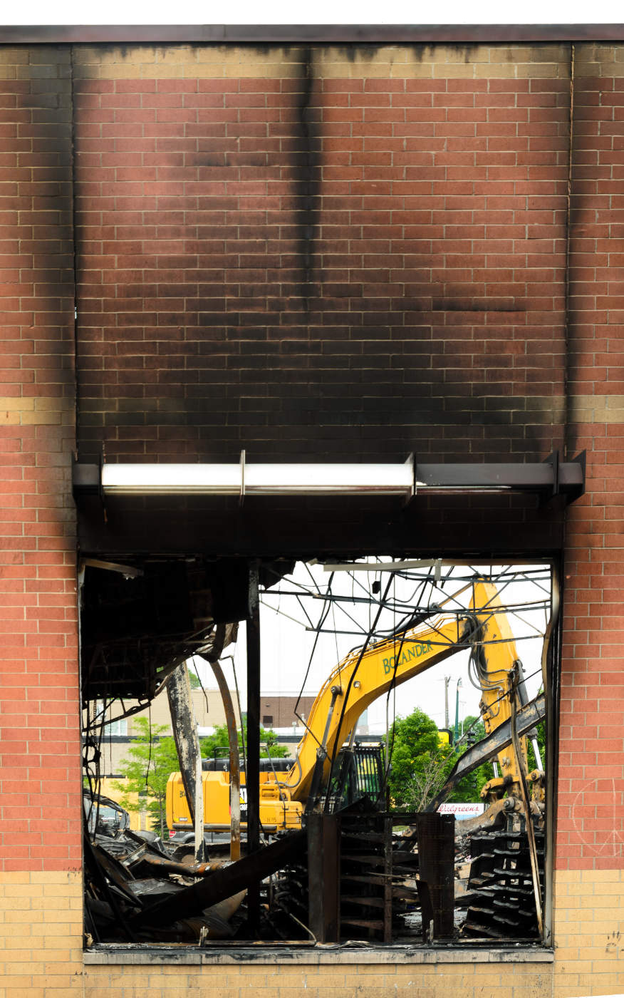 Looking through a burnt hole in a brick wall with a construction crane in the background