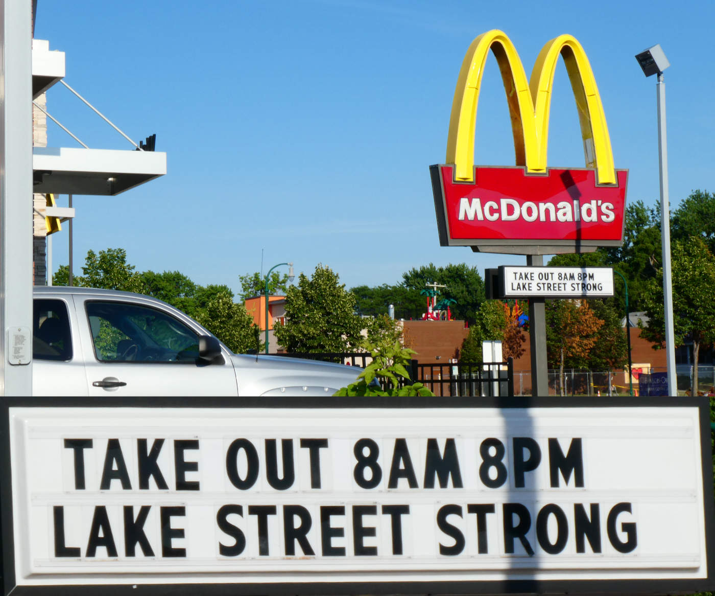 McDonalds street sign with golden arches and sign reading: Take out 8am 8pm - Lake Street Strong