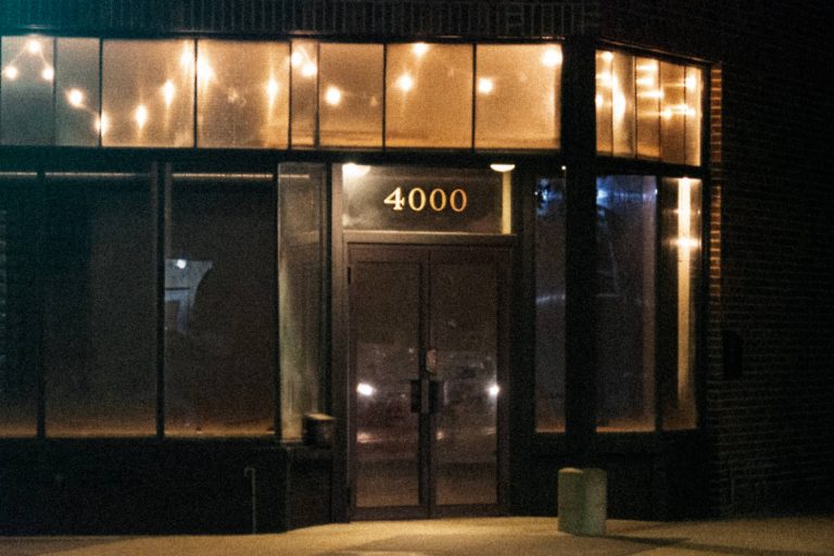 dark storefront windows with overhead lights and just an address of 4000 on a transom window