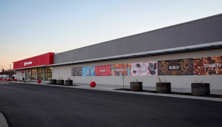 long wall of building with a red Target store entrance at far end and a colorful mural across the wall to the near end with the words: We Stand Together. We Build Together.