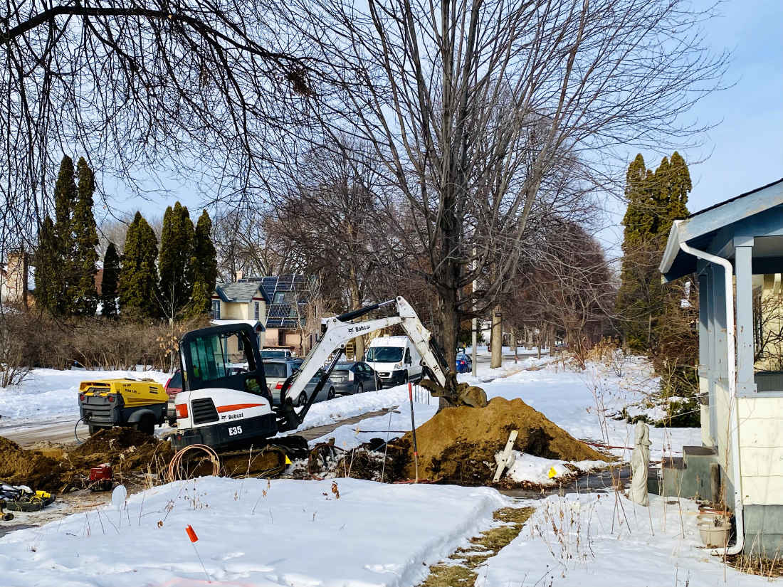 construction equipment digging a hole next to a mound of dirt in a winter yard