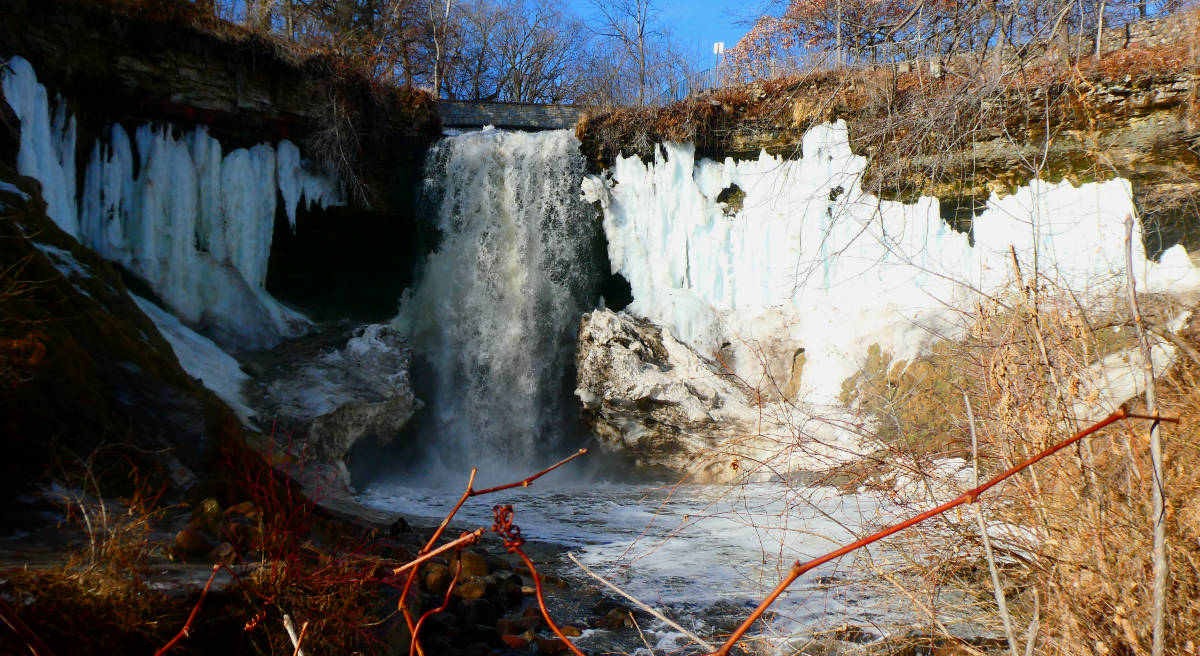 Picturesque scene of waterfall framed by icy cliffs with blue sky overhead