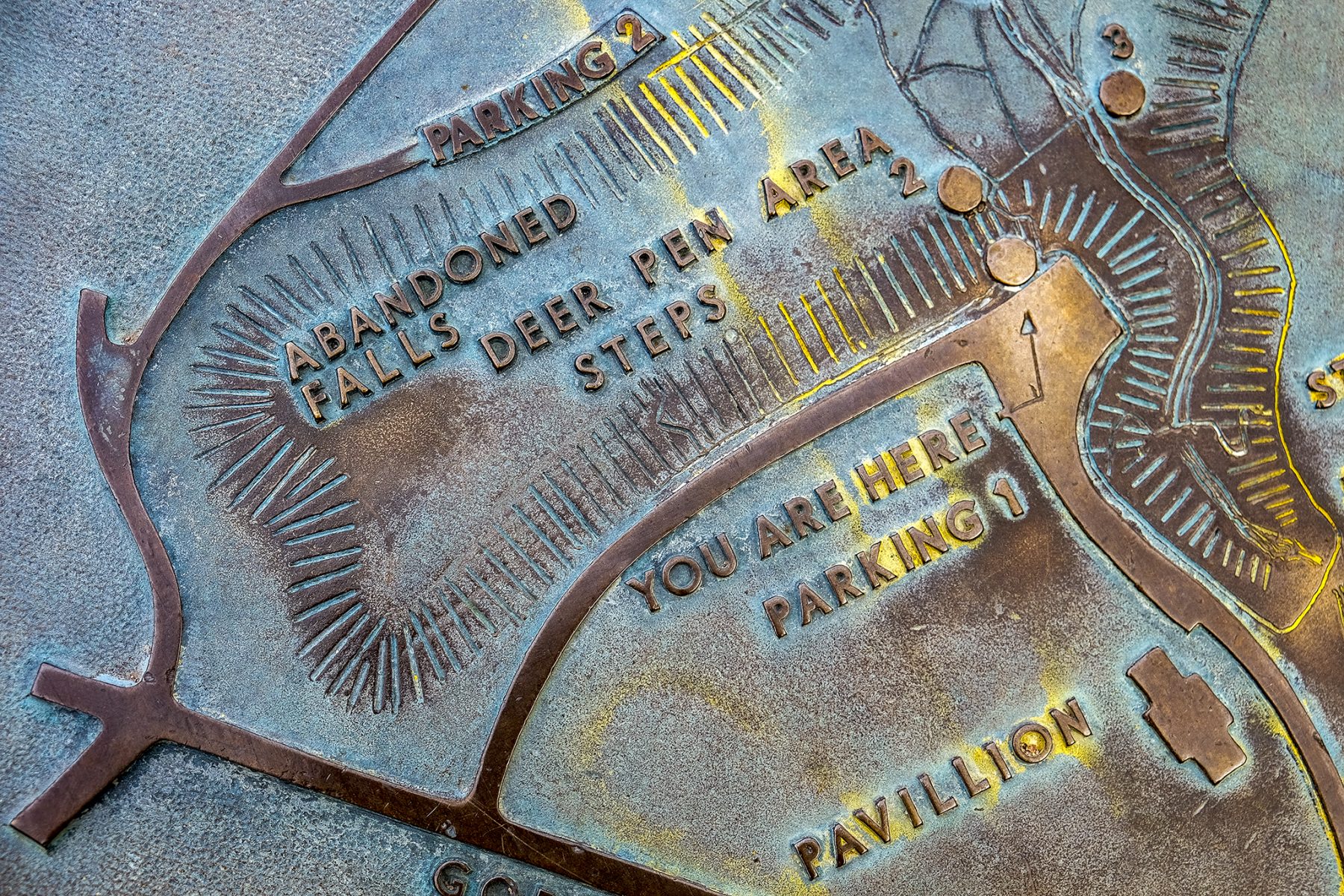 An oxidized bronze plaque by Bridge No. 2 in Minnehaha Park indicates where you are on a map.